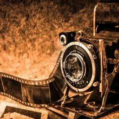 Antyczna kamera i rolka kliszy, świadkowie pierwszych fotografii, w sepia tonacji.