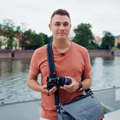 Mężczyzna z aparatem, gotowy do uchwycenia miejskiego krajobrazu. Pokazuje zaawansowane techniki fotograficzne.