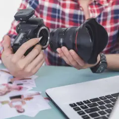 Fotograf przygotowuje sprzęt. Zastanawia się, czy robienie zdjęć z ukrycia jest karalne, przeglądając wydrukowane fotografie.