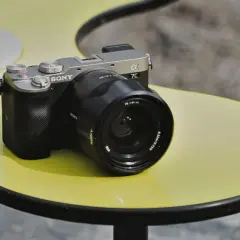 Srebrno-czarny aparat Sony a7c z obiektywem na żółtym stoliku.