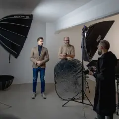 W studiu fotograficznym mężczyźni przygotowują się do sesji. Wrota do świata fotografii otwierają się dzięki profesjonalnemu sprzętowi.