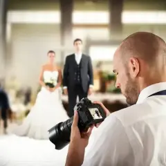 Fotograf uchwycił parę młodą, przygotowując się do sesji. Zastanawiasz się, ile kosztuje fotograf na wesele?