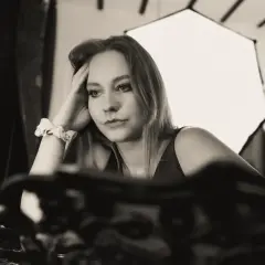 Kobieta podczas sesji buduarowej, z ręką na skroni, w zamyśleniu. W tle softbox i lampa pierścieniowa.