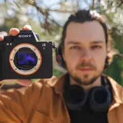Mężczyzna prezentuje aparat Sony a7riv z obiektywem E-mount.