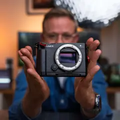 Mężczyzna trzyma aparat Lumix, gotowy do uchwycenia każdej chwili. To jego pelna klatka marzeń.