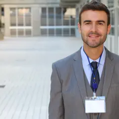 Uśmiechnięty mężczyzna w garniturze, gotowy na ważne spotkanie. To jego zdjęcie do identyfikatora.