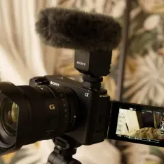 Kamera Sony Alpha z mikrofonem na gorącej stopce, gotowa do nagrywania. Idealny sprzęt do tworzenia treści, np. vlogów.