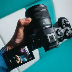 Dłoń trzyma aparat Canon z obiektywem RF 45mm. Wyświetlacz pokazuje zdjęcie.