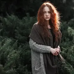 Ruda dziewczyna w otoczeniu zieleni. Minimalizm w fotografii podkreśla jej naturalne piękno i spokój.