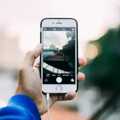 Ręka trzyma smartfon, na ekranie którego widać widok miasta. Robię sobie selfie z widokiem na dachy i budynki.