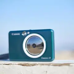 Niebieski aparat Canon Zoemini S2, idealny aparat na wakacje, gotowy do łapania wspomnień.