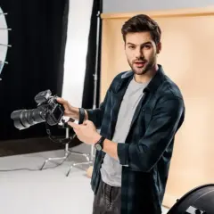 Młody fotograf z aparatem w studio. Świetna robota!