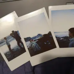 Zdjęcia z Instax pokazują, jak robić zdjęcia na plaży: chłopak fotografuje drugiego, para siedzi na skałach, a trzeci chłopiec patrzy na morze.