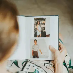 Osoba przegląda album ze zdjęciami: kobieta w ciąży i młody mężczyzna.