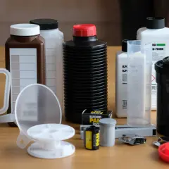 Niezbędne akcesoria do domowej ciemni fotograficznej: butelki z odczynnikami, menzurki, klisza, bębenek i inne.