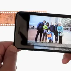 Telefon wyświetla zdjęcie rodziny, obok negatyw filmowy. Dowiedz się, jak odwrócić kolory zdjęcia na telefonie, by uzyskać ciekawy efekt.