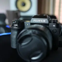 Czarny aparat Fujifilm xh2s z obiektywem i osłoną obiektywu na czarnym blacie.