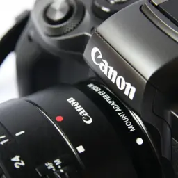 Czarne body i obiektyw lustrzanki Canon, idealne dla początkujących. Widoczne oznaczenia trybów fotografowania.