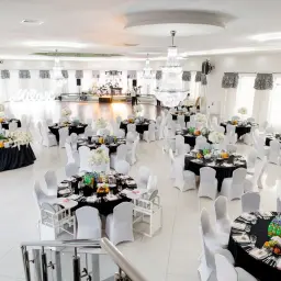 Elegancka sala weselna z czarnymi obrusami i białymi krzesłami. Zastanawiasz się, ile bierze fotograf za wesele?