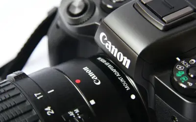 Część czarnego aparatu Canon z obiektywem. Idealna lustrzanka na początek dla każdego pasjonata fotografii.