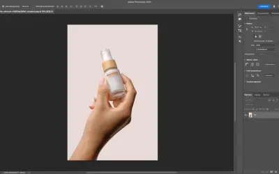 Dłoń trzymająca buteleczkę kosmetyku na jasnym tle. Program Photoshop pokazuje narzędzia, jak usunąć tło ze zdjęcia, aby wyizolować produkt.