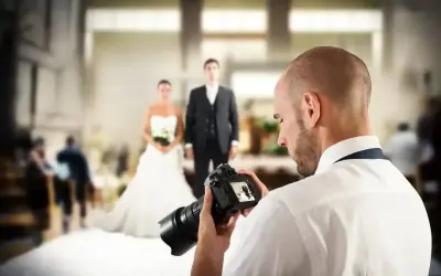 Fotograf uchwycił parę młodą, przygotowując się do sesji. Zastanawiasz się, ile kosztuje fotograf na wesele?