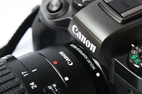 Część czarnego aparatu Canon z obiektywem. Idealna lustrzanka na początek dla każdego pasjonata fotografii.