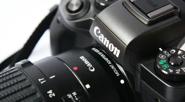 Część czarnego aparatu Canon z obiektywem. Idealna lustrzanka na początek dla każdego pasjonata fotografii.