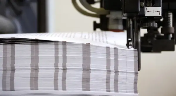 Stos papieru o wymiarach formatu a0 czeka na obróbkę w maszynie drukarskiej.