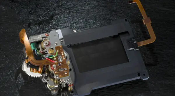 Mechanizm migawki szczelinowej aparatu z taśmami flex i elementami elektronicznymi.