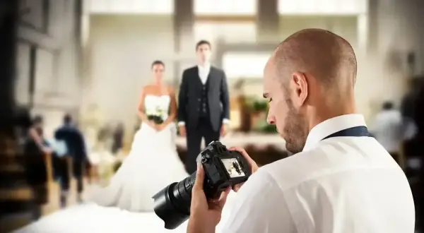 Fotograf uchwycił parę młodą, przygotowując się do sesji. Zastanawiasz się, ile kosztuje fotograf na wesele?