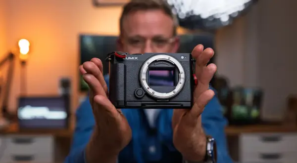 Mężczyzna trzyma aparat Lumix, gotowy do uchwycenia każdej chwili. To jego pelna klatka marzeń.