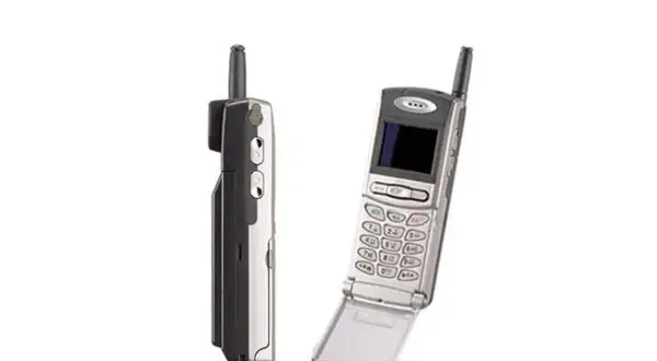 Dwa stare telefony komórkowe, jeden z nich to prawdopodobnie pierwszy telefon z aparatem, z charakterystyczną antenką i klapką.