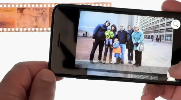 Telefon wyświetla zdjęcie rodziny, obok negatyw filmowy. Dowiedz się, jak odwrócić kolory zdjęcia na telefonie, by uzyskać ciekawy efekt.