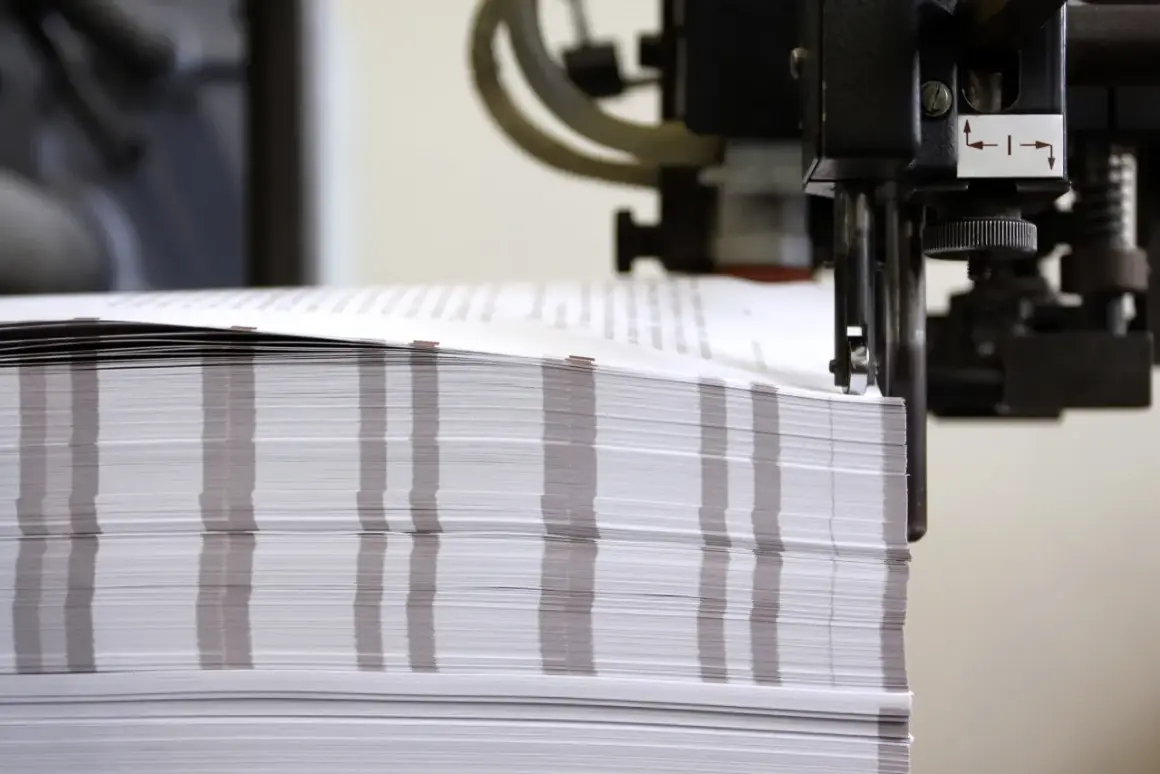 Stos papieru o wymiarach formatu a0 czeka na obróbkę w maszynie drukarskiej.
