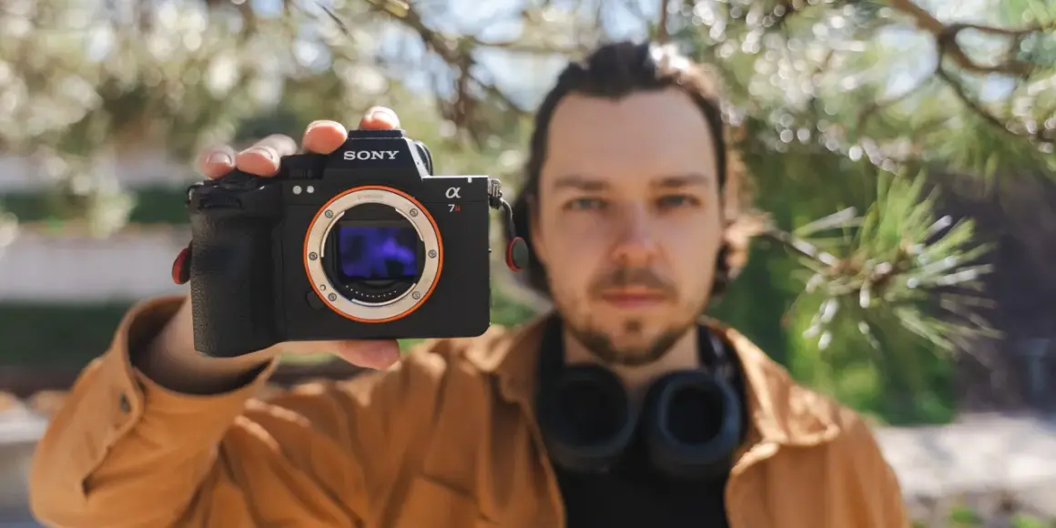 Mężczyzna prezentuje aparat Sony a7riv z obiektywem E-mount.