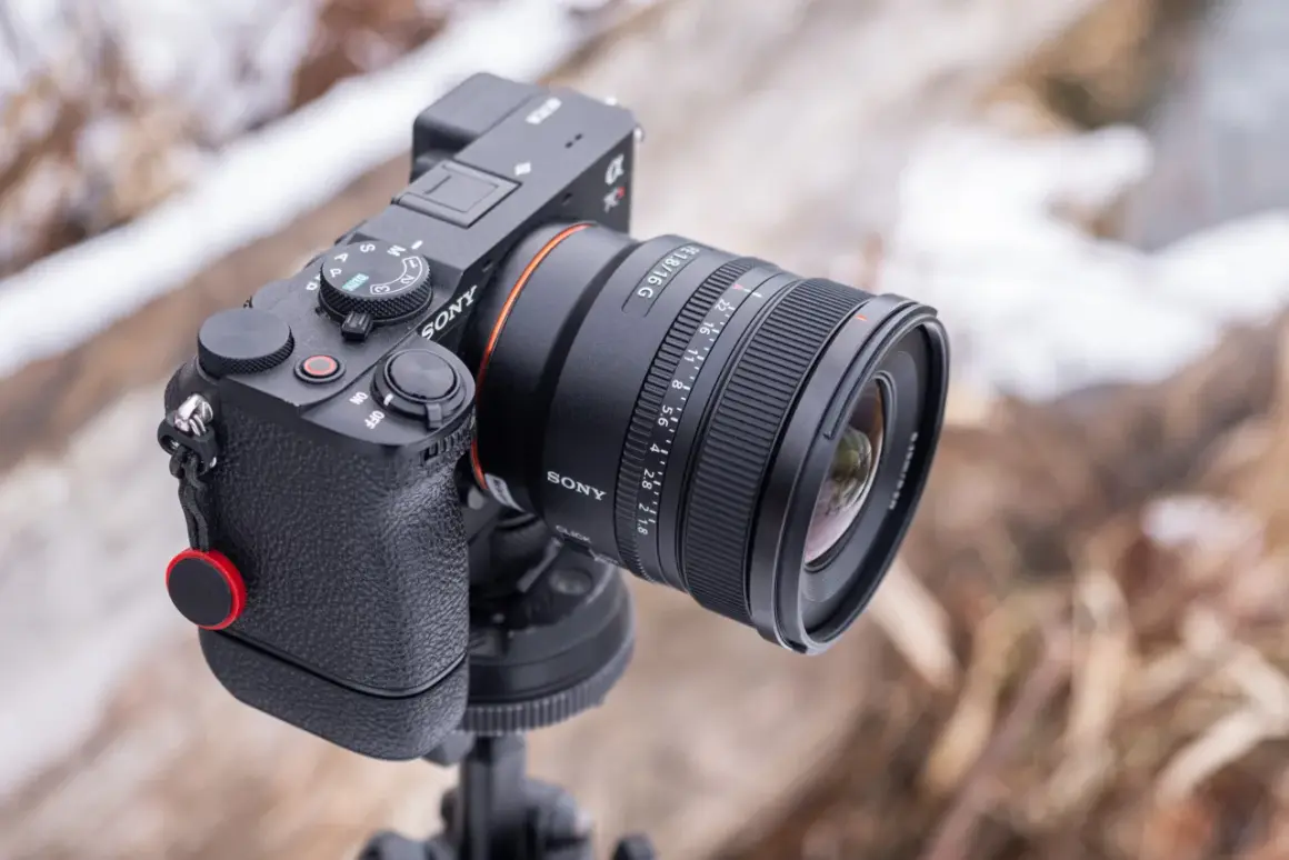 Sony A290 z obiektywem FE 1.8/16 G na statywie, w tle zimowy krajobraz.