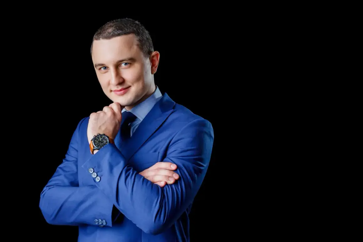 Mężczyzna w niebieskiej marynarce, z rękami skrzyżowanymi na piersi, zastanawia się, jak wkleić zdjęcie do CV.