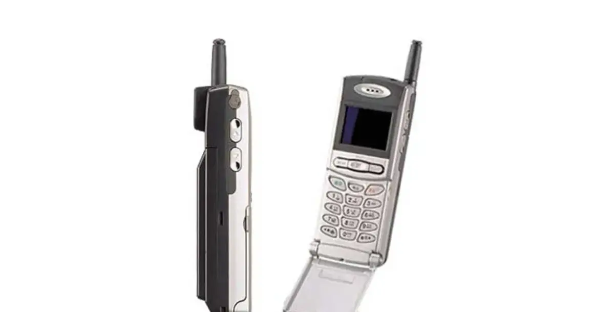 Dwa stare telefony komórkowe, jeden z nich to prawdopodobnie pierwszy telefon z aparatem, z charakterystyczną antenką i klapką.