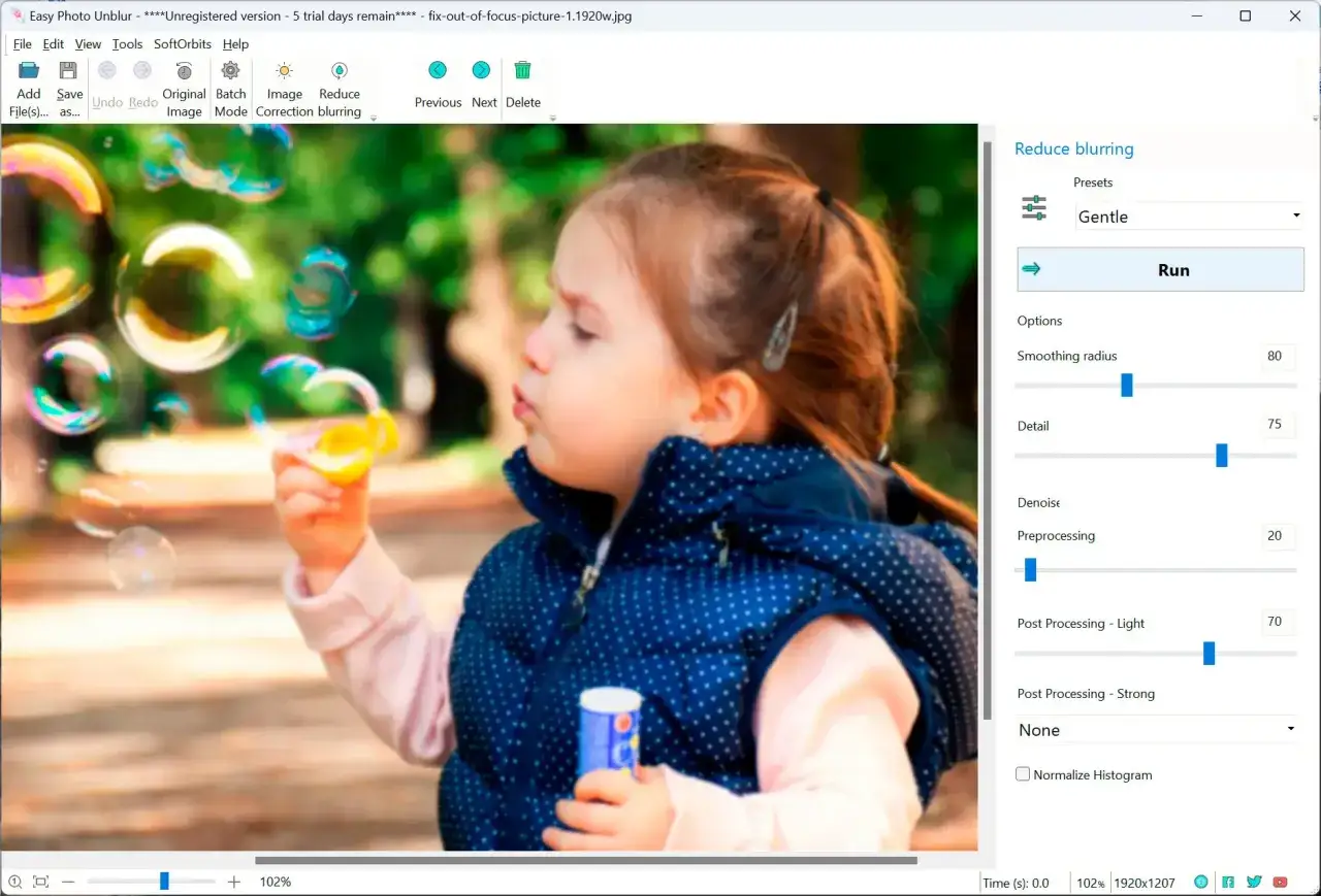 Dziewczynka puszcza bańki. Program Easy Photo Unblur pokazuje, jak wyostrzyć zdjęcie, z opcjami wygładzania i detalu.