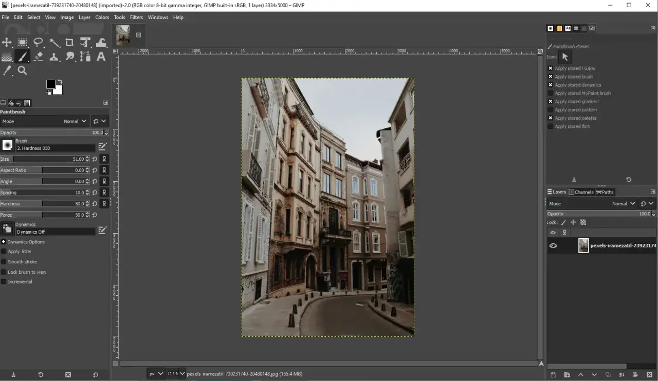 Edytor graficzny GIMP, darmowy photoshop, z otwartym zdjęciem wąskiej uliczki między kamienicami.