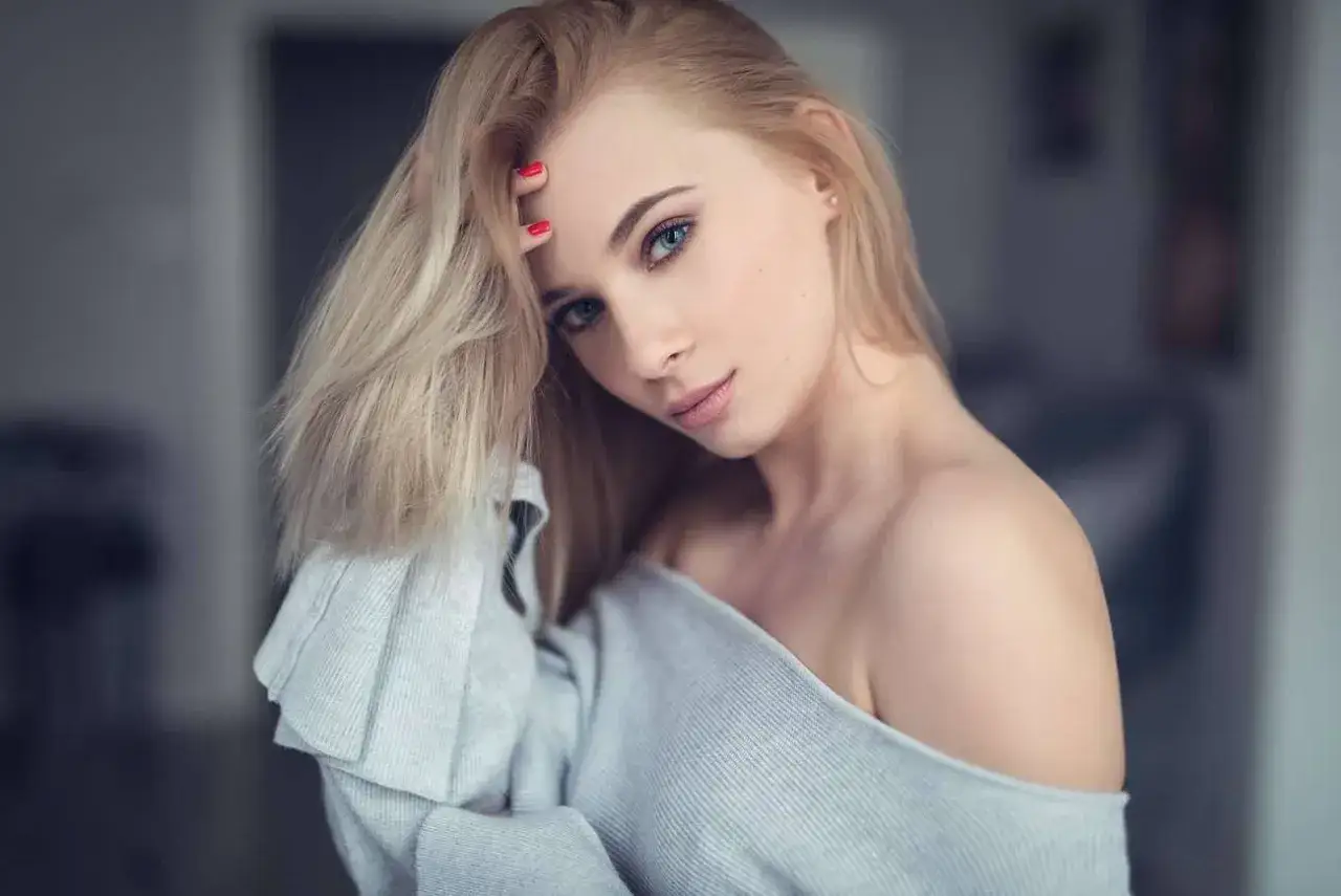 Blondynka z niebieskimi oczami, zmysłowo dotykająca włosów. Sprawdź, jaka jest sesja zdjęciowa cena.