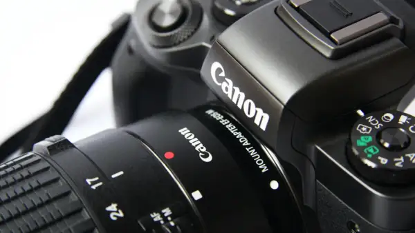 Część czarnego aparatu Canon z obiektywem. Idealna lustrzanka na początek dla każdego pasjonata fotografii.