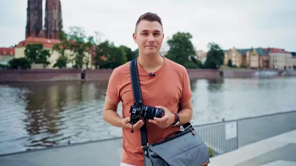 Mężczyzna z aparatem, gotowy do uchwycenia miejskiego krajobrazu. Pokazuje zaawansowane techniki fotograficzne.