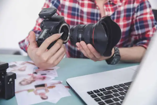 Fotograf przygotowuje sprzęt. Zastanawia się, czy robienie zdjęć z ukrycia jest karalne, przeglądając wydrukowane fotografie.