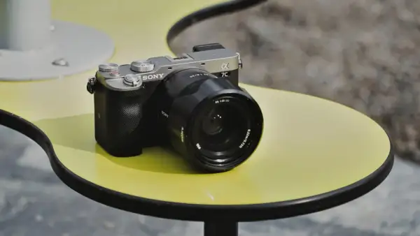 Srebrno-czarny aparat Sony a7c z obiektywem na żółtym stoliku.