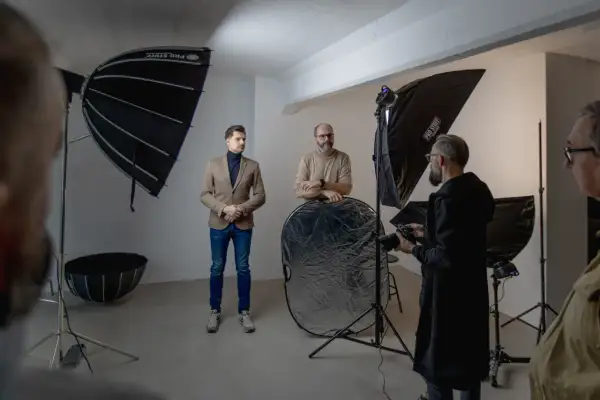 W studiu fotograficznym mężczyźni przygotowują się do sesji. Wrota do świata fotografii otwierają się dzięki profesjonalnemu sprzętowi.