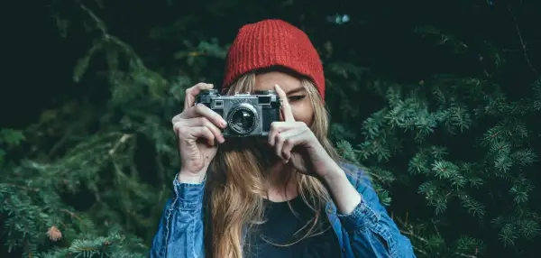 Dziewczyna w czerwonej czapce i dżinsowej kurtce trzyma aparat, gotowa do uchwycenia piękna przyrody. To jej dzień fotografa.