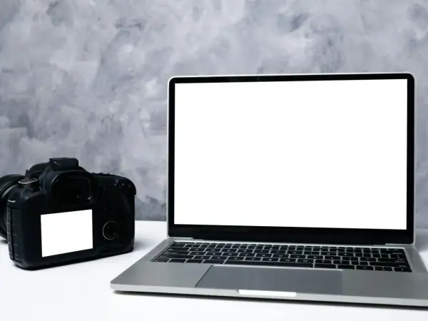 Aparat fotograficzny i laptop z pustym ekranem, gotowe do transferu zdjęć. Dowiedz się, jak zgrać zdjęcia z aparatu na komputer.