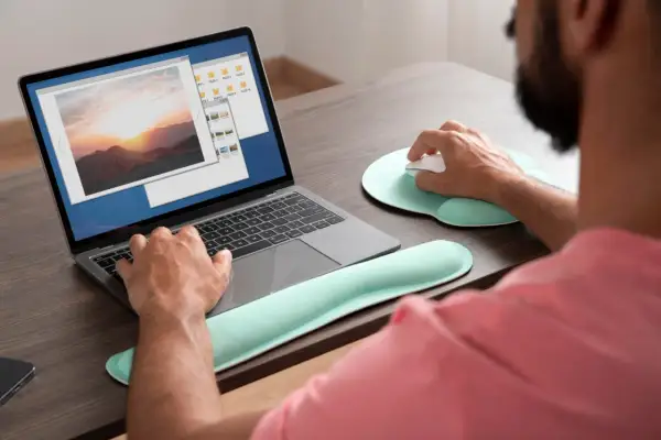 Mężczyzna pracuje na laptopie, przeglądając zdjęcia. Może szukać sposobu, jak wyostrzyć zdjęcie, aby poprawić jego jakość.